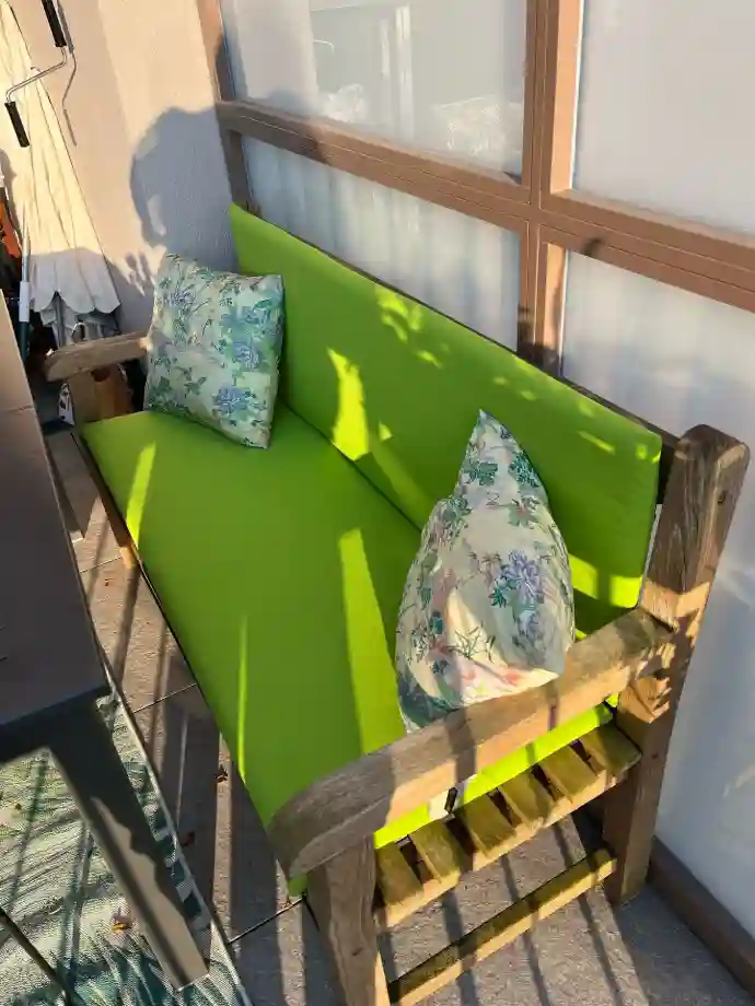 Neues Polster in kräftigem Grün für die Gartenbank Gartenbank mit frisch bezogenem grünem Polster und gemusterten Outdoor-Kissen auf der Terrasse